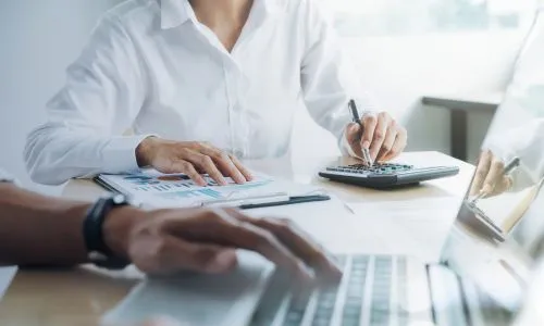 Dietetyk liczący koszty na kalkulatorze przy laptopie - własny cennik zamiast kopiowania stawek konkurencji