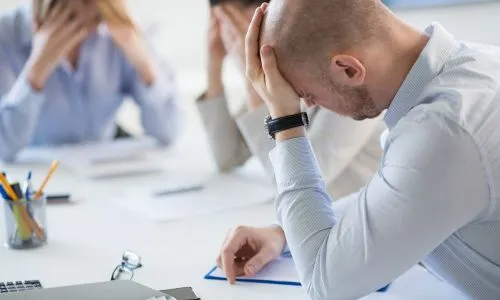 Zmartwiony najemca przy biurku - kosztowne frycowe przy wynajmie pierwszego gabinetu dietetycznego
