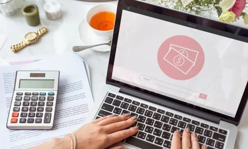 Laptop z ikoną płatności i kalkulator na biurku - pakiety i abonamenty w cenniku gabinetu dietetycznego